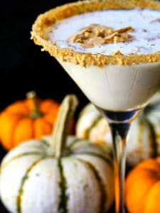 creamy pumpkin martini with a graham cracker rim and pumpkins in background