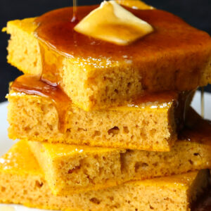 Pumpkin Sheet Pan Pancakes stacked with butter and syrup