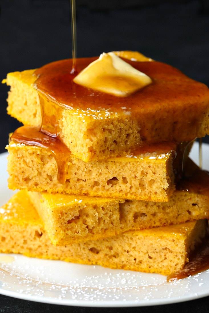 Pumpkin Sheet Pan Pancakes stacked with butter and syrup