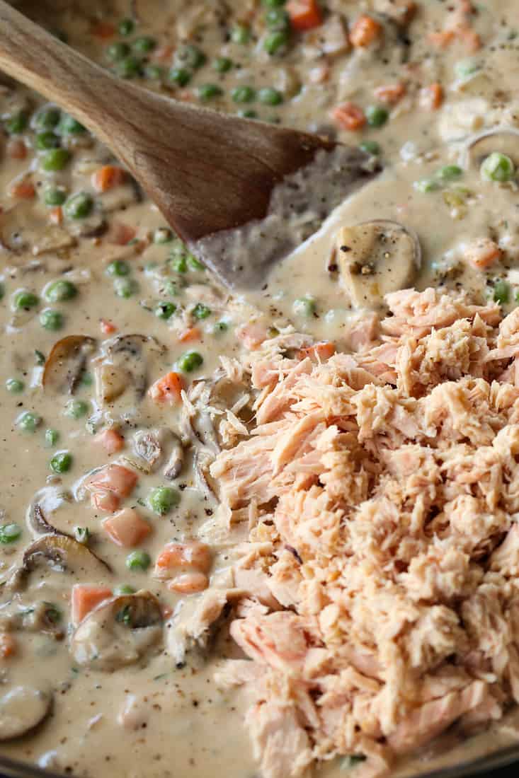 Canned tuna being added to tuna noodle casserole filling