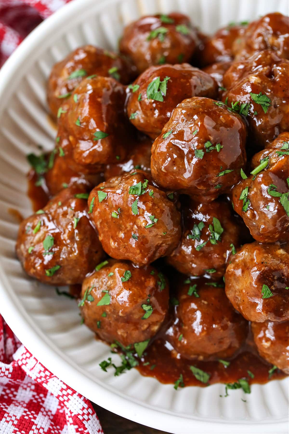 BBQ Party Meatballs are one of our favorite party appetizers! Homemade meatballs that are oven baked and tossed in a sweet and spicy sauce. meatballs in a white bowl with bbq sauce
