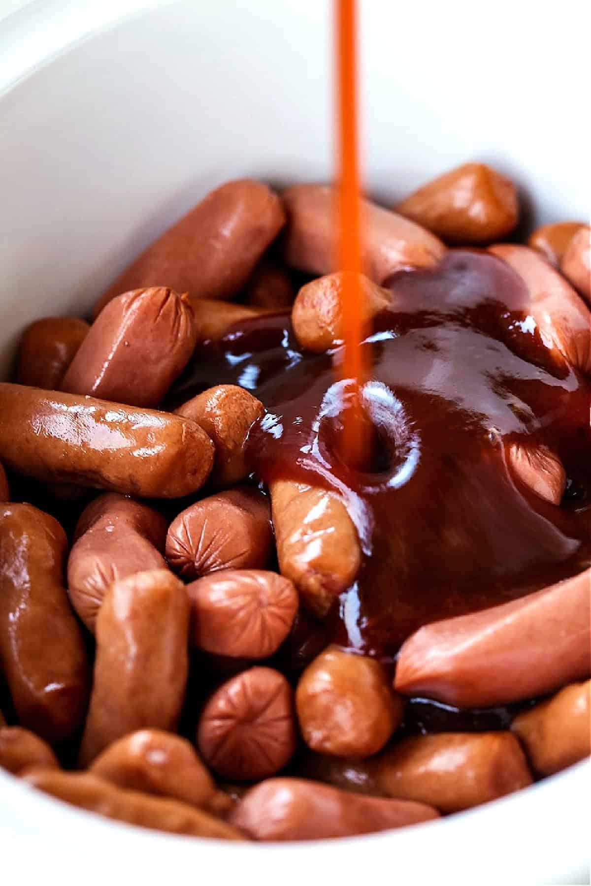 sauce pouring over little hot dogs in a crock pot