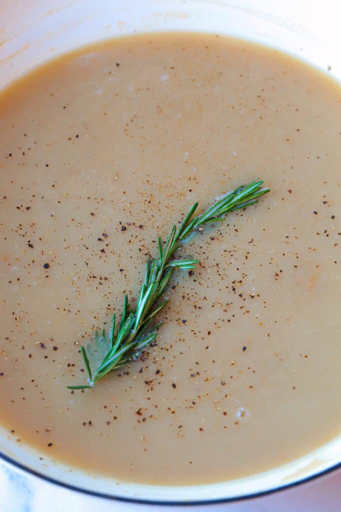 You're going to want to pour this Cranberry Turkey Gravy on everything! Cranberry sauce and bourbon add so much flavor than regular gravy! gravy in skillet with pepper and rosemary