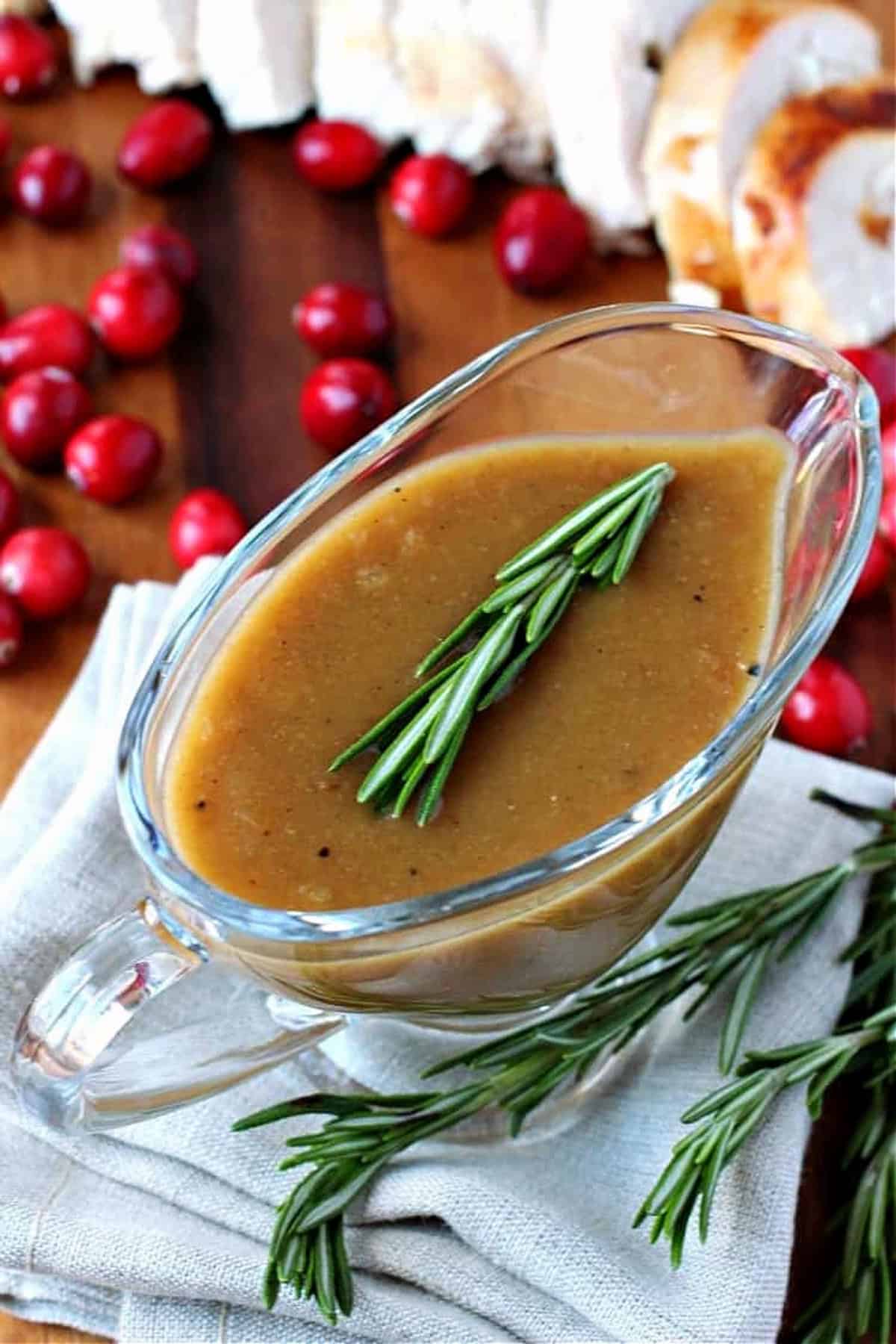 You're going to want to pour this Cranberry Turkey Gravy on everything! Cranberry sauce and bourbon add so much flavor than regular gravy! turkey gravy in a gravy boat with turkey in background