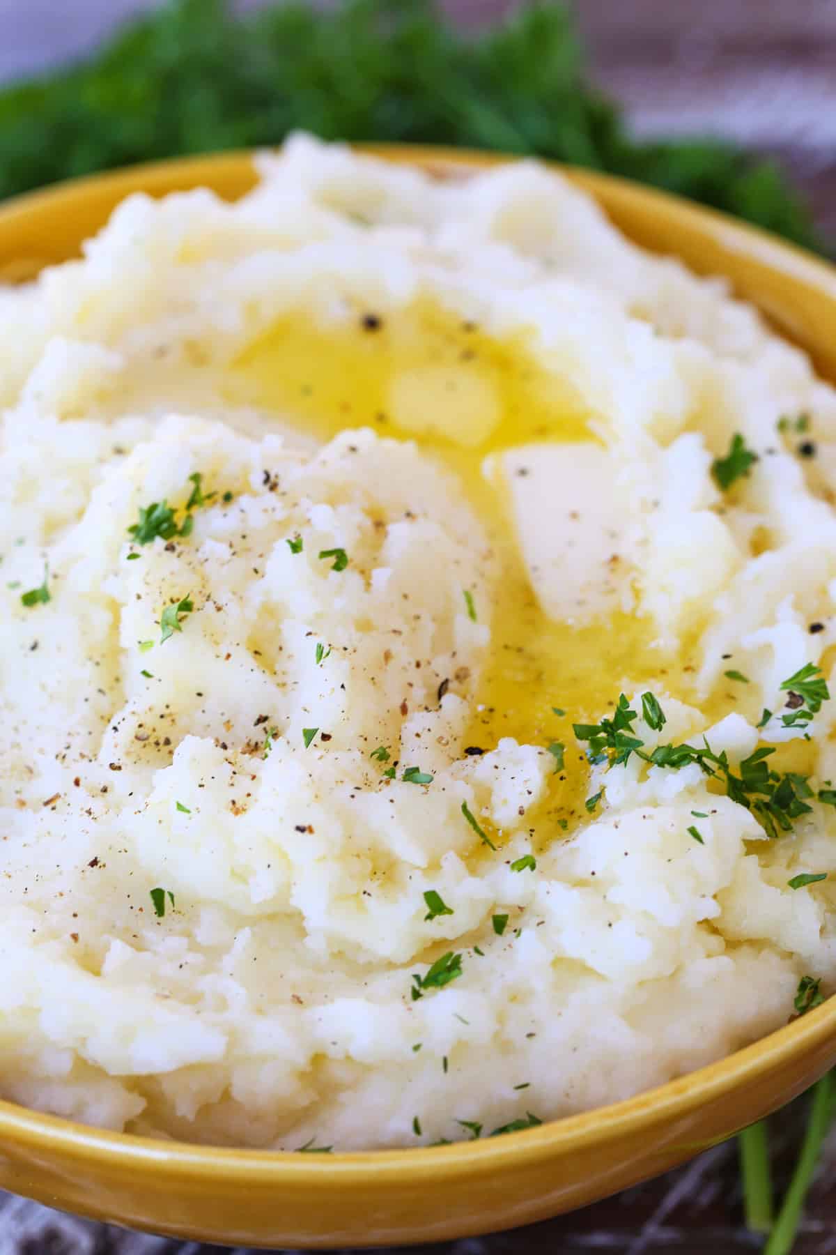 Our Fluffy Mashed Potatoes are so smooth and creamy, you won't make them any other way! A key tool makes these potatoes the best! mashed potatoes in bowl with melted butter