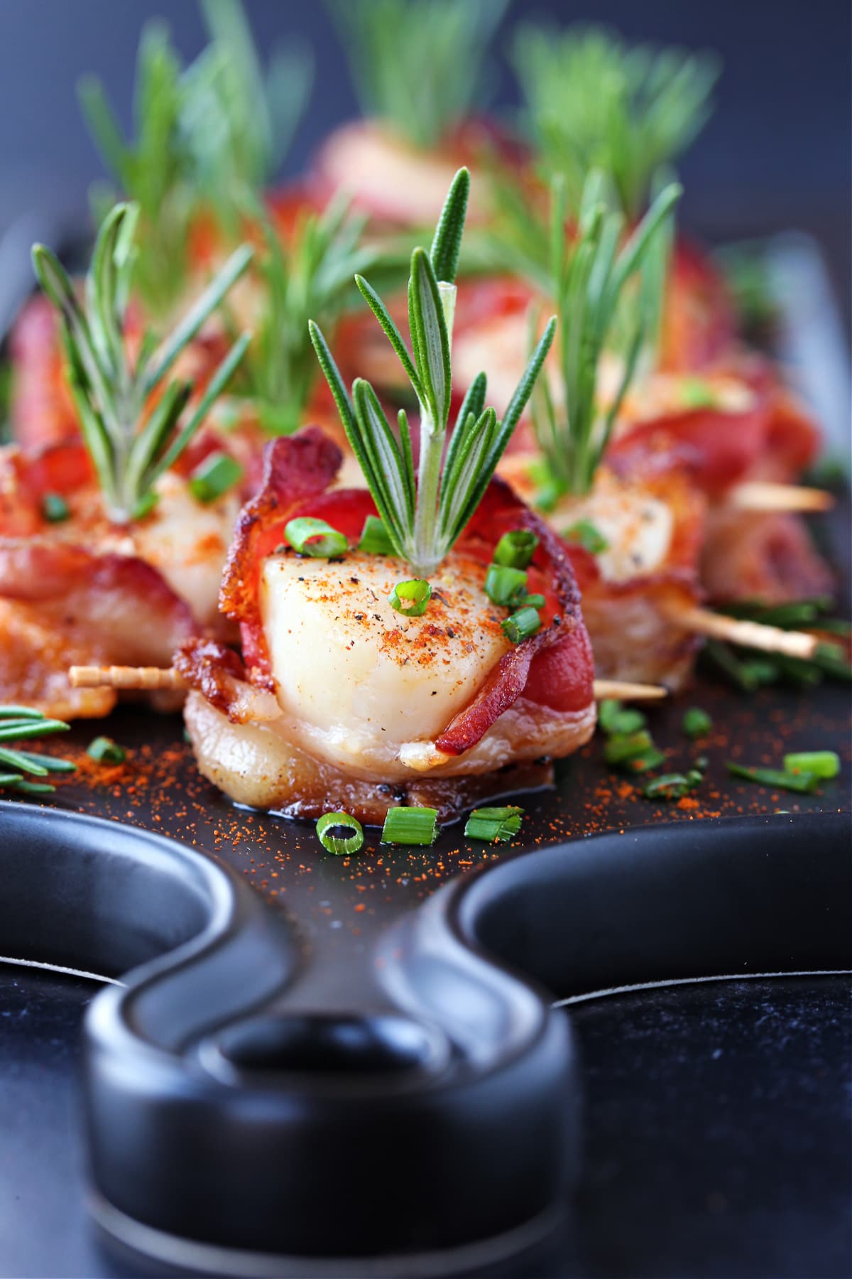 Bacon Wrapped Scallops are a holiday classic appetizer! We've got a hack to make sure that the bacon is actually crispy and not rubbery! scallops wrapped with bacon with rosemary garnish