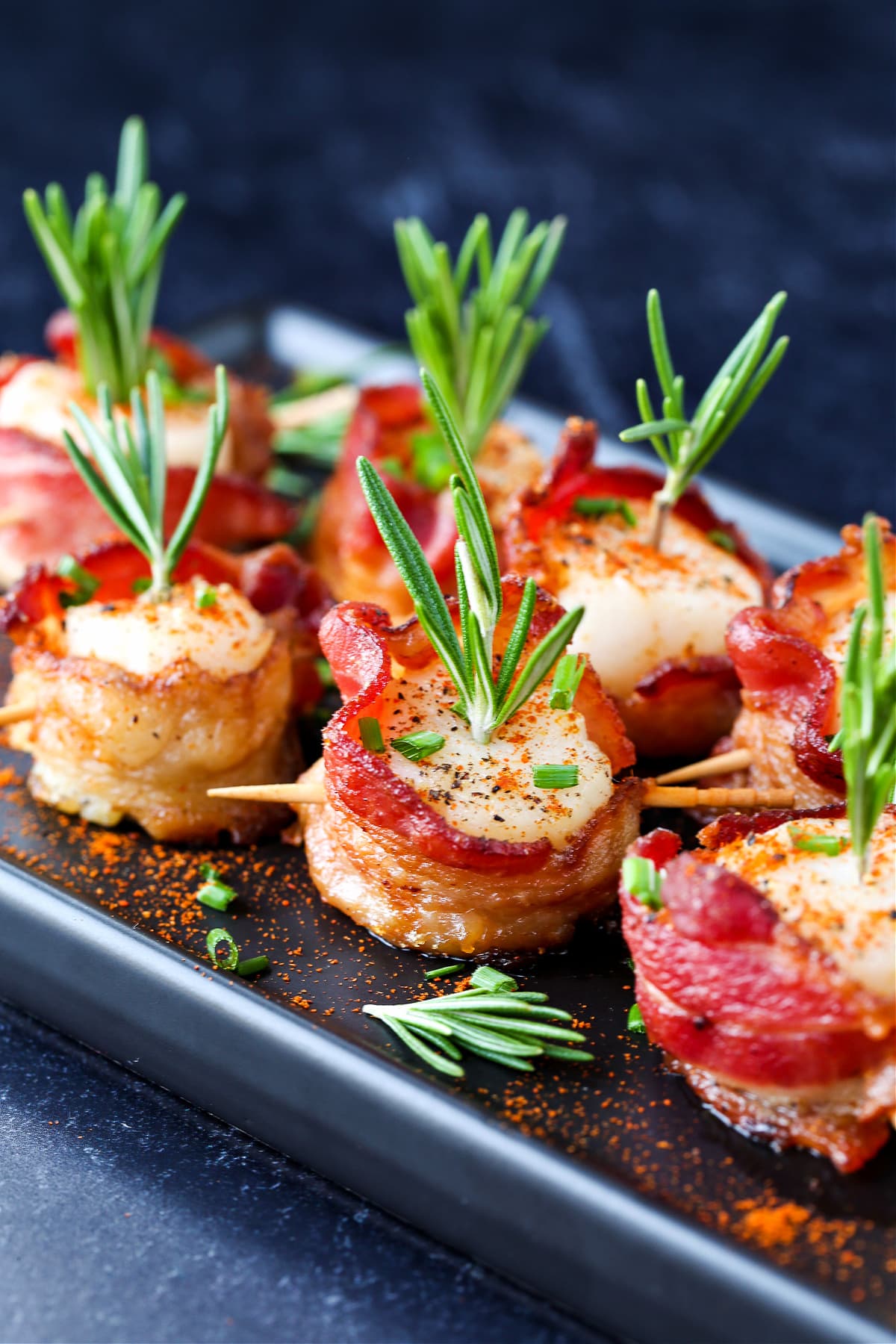 scallops wrapped in bacon on platter garnished with rosemary