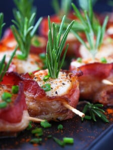 bacon wrapped scallops on black platter with toothpicks