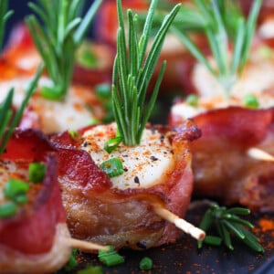 bacon wrapped scallops on black platter with toothpicks