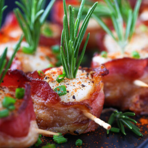 bacon wrapped scallops on black platter with toothpicks