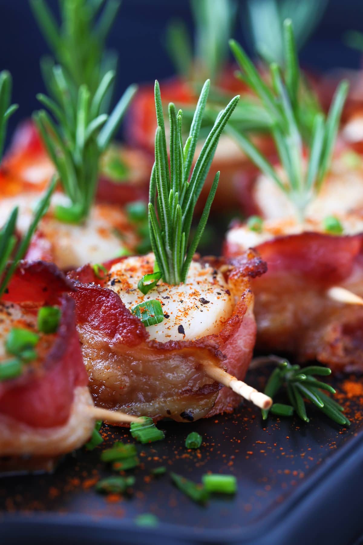 bacon wrapped scallops on black platter with toothpicks