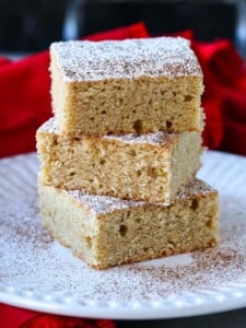 Eggnog Cookie Bars stacked on white plate with powdered sugar