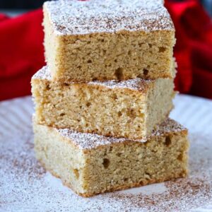 Eggnog Cookie Bars stacked on white plate with powdered sugar