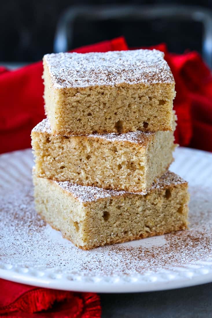 Eggnog Cookie Bars stacked on white plate with powdered sugar