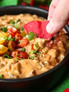 Sausage queso dip with tortilla chip dipping in