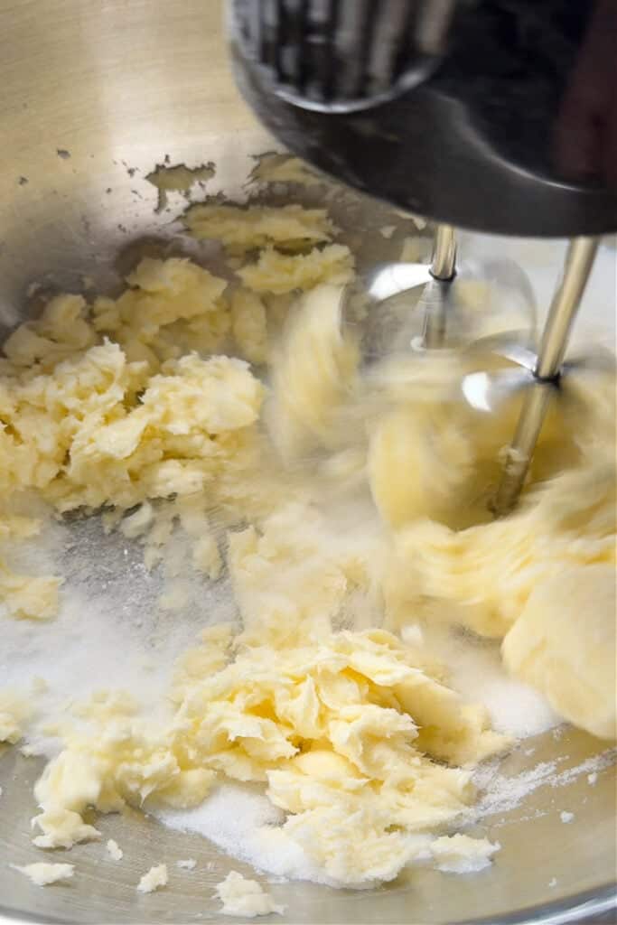 Our Limoncello Lemon Bars are a fun party dessert! Zesty lemon bars with a thick, buttery shortbread topped with a sweet and creamy custard. hand mixer blending a shortbread crust