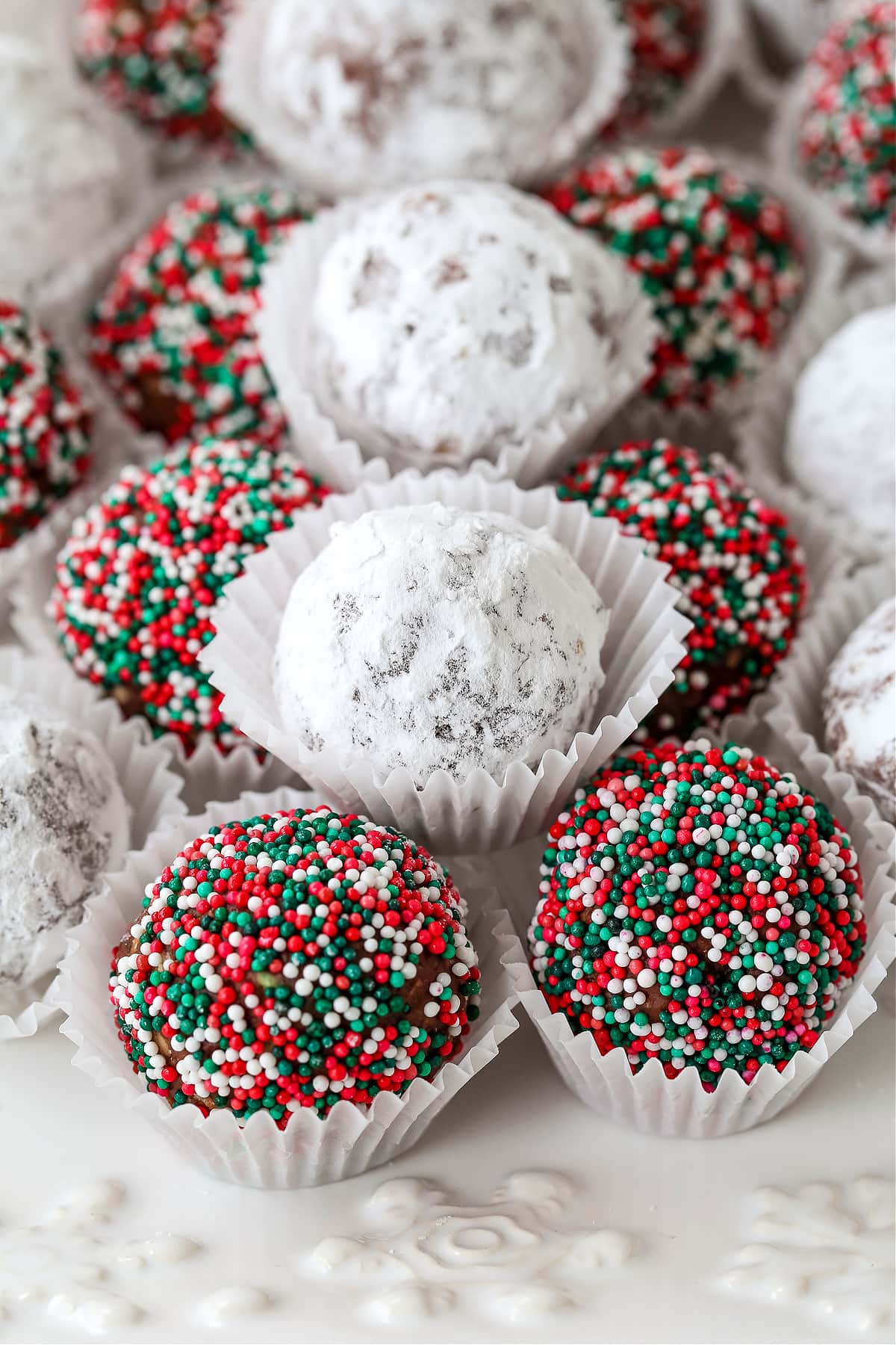 Rum Balls are a classic holiday dessert! This make ahead, festive treat can be customized for any occasion and pack a big punch of rum! rum balls with sprinkles and powdered sugar
