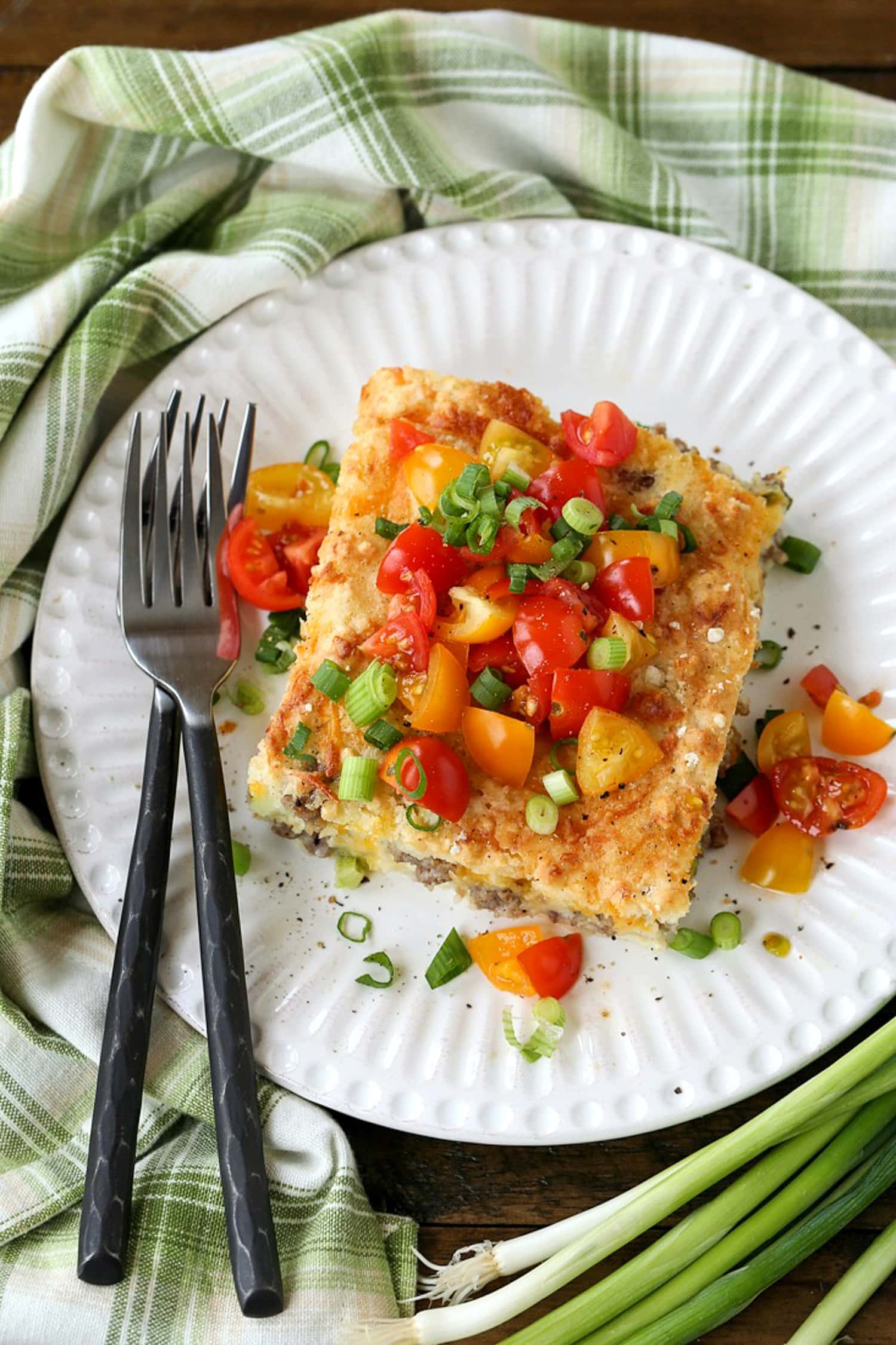 slice of breakfast casserole on plate with tomatoes