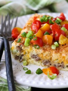 Sausage Breakfast Casserole on plate with tomatoes and scallions