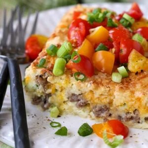 Sausage Breakfast Casserole on plate with tomatoes and scallions