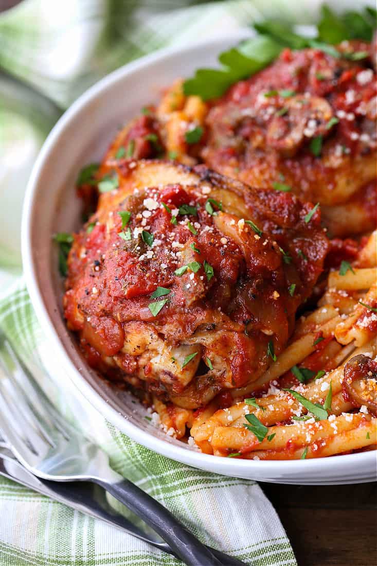 Tender chicken thighs in a bowl with tomato sauce and pasta