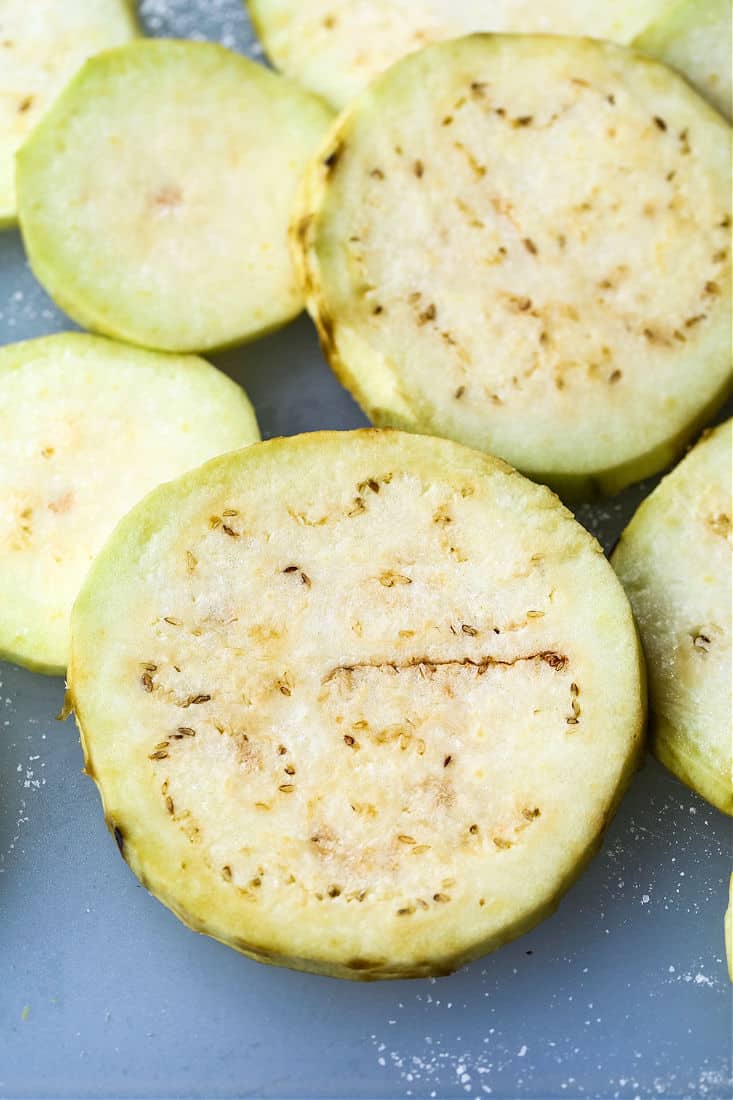 Several slices of eggplant being salted before they're fried.