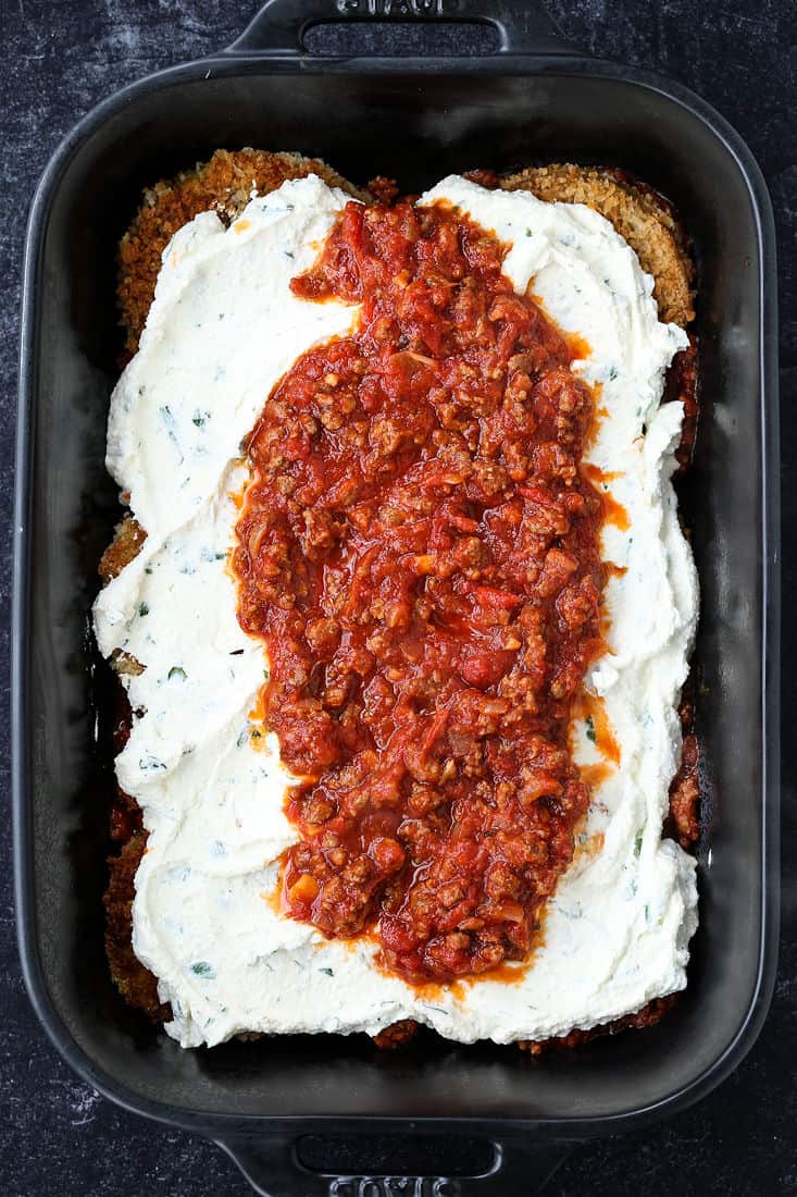 Layers of fried eggplant, ricotta cheese and meat sauce in a pan.