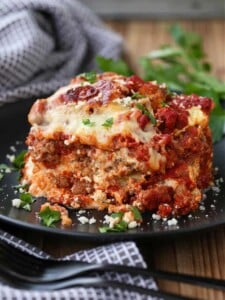 A square of eggplant parmesan on a plate next to a napkin.