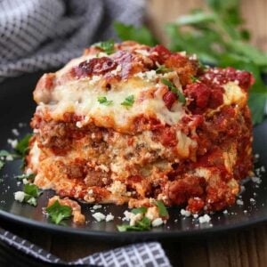 A square of eggplant parmesan on a plate next to a napkin.