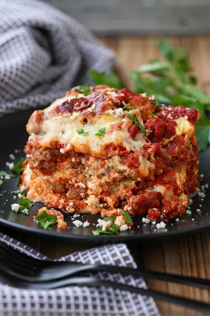 A square of eggplant parmesan on a plate next to a napkin.