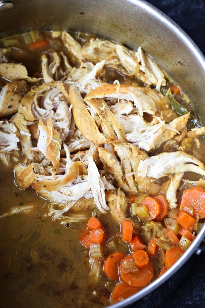 shredded chicken and vegetables in a pot for making chicken soup