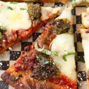 Slice of Sausage Pesto Pizza drizzled with olive oil