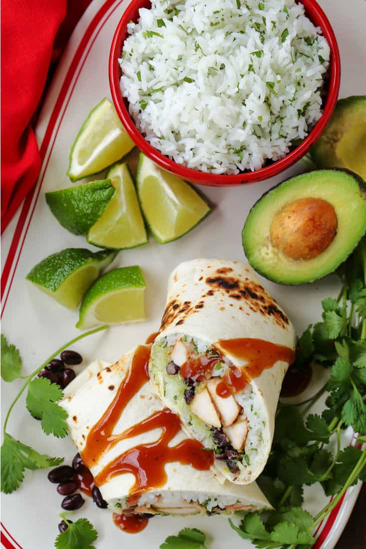 Chicken Burritos sliced on a plate with avocado and rice