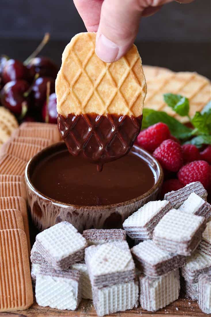 Cookie wafer being dipped into chocolate fondue