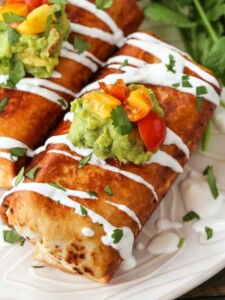 Chicken Chimichangas on a plate with sour cream drizzle