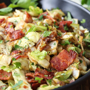 fried cabbage with bacon in black bowl with napkin