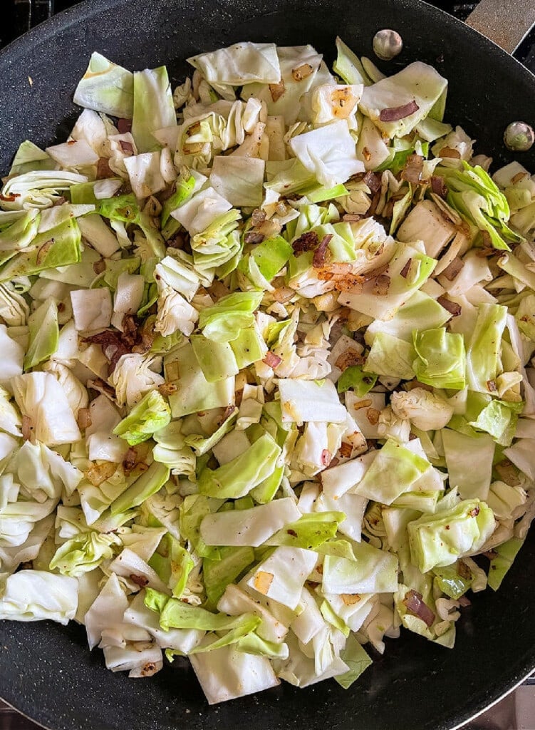 Fried Cabbage with Bacon is an easy side dish that goes with many meals! Sweet cabbage with crispy, salty bacon is the perfect combination! diced cabbage with onions in a skillet