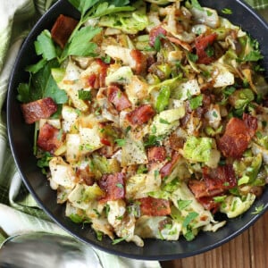 fried cabbage with bacon in a black bowl with spoon