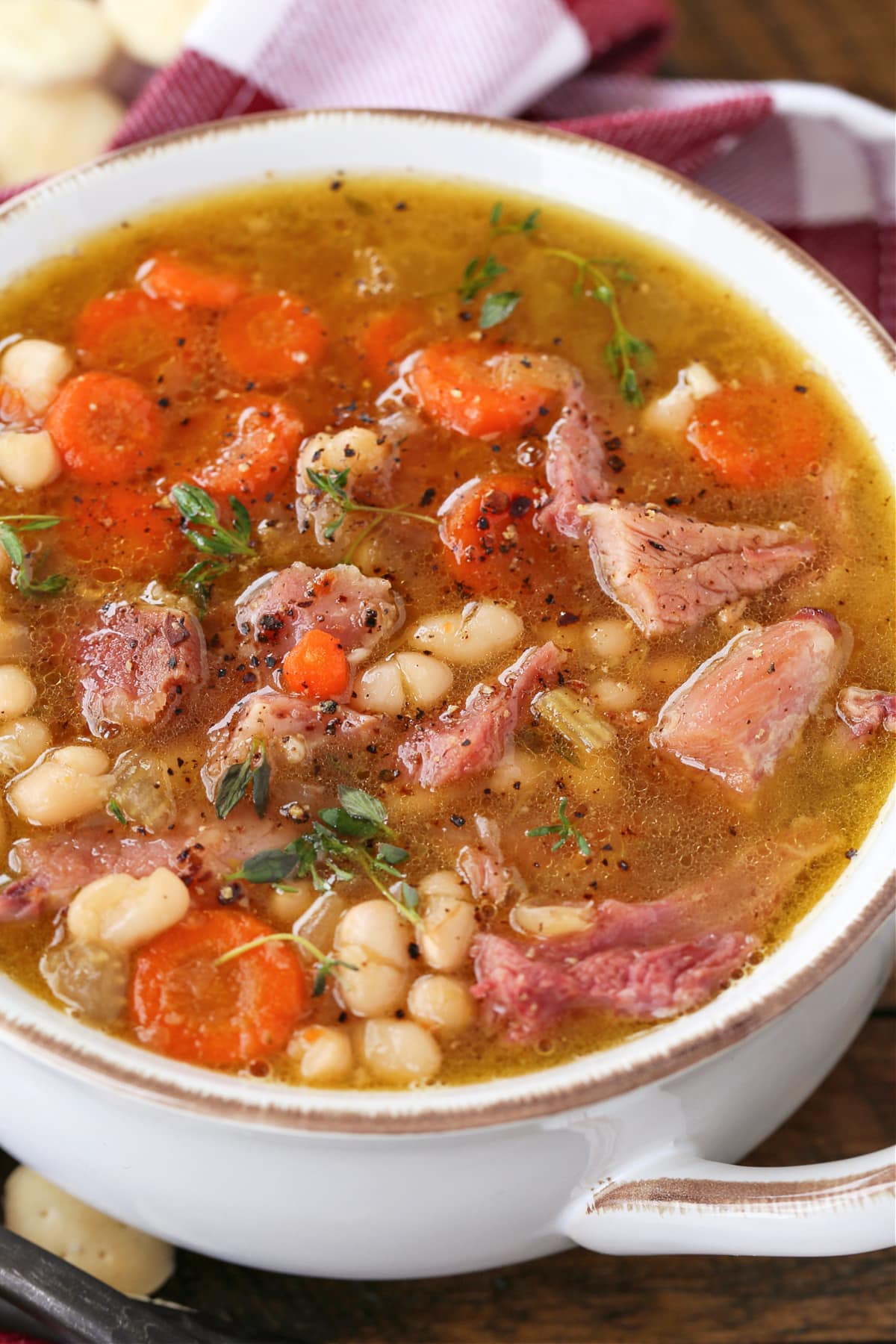 Make this comforting Navy Bean Soup with your leftover ham bone! A hearty soup loaded with vegetables in a homemade ham bone broth. ham and bean soup in white bowl with napkin