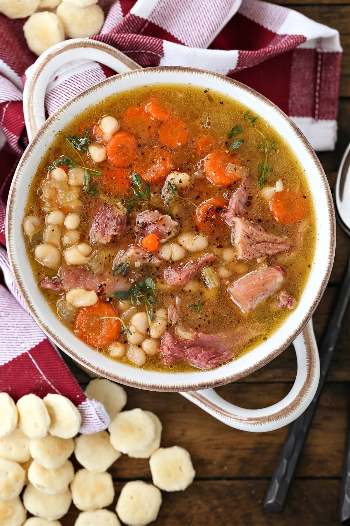 Make this comforting Navy Bean Soup with your leftover ham bone! A hearty soup loaded with vegetables in a homemade ham bone broth. navy bean soup in a white crock with crackers on the side