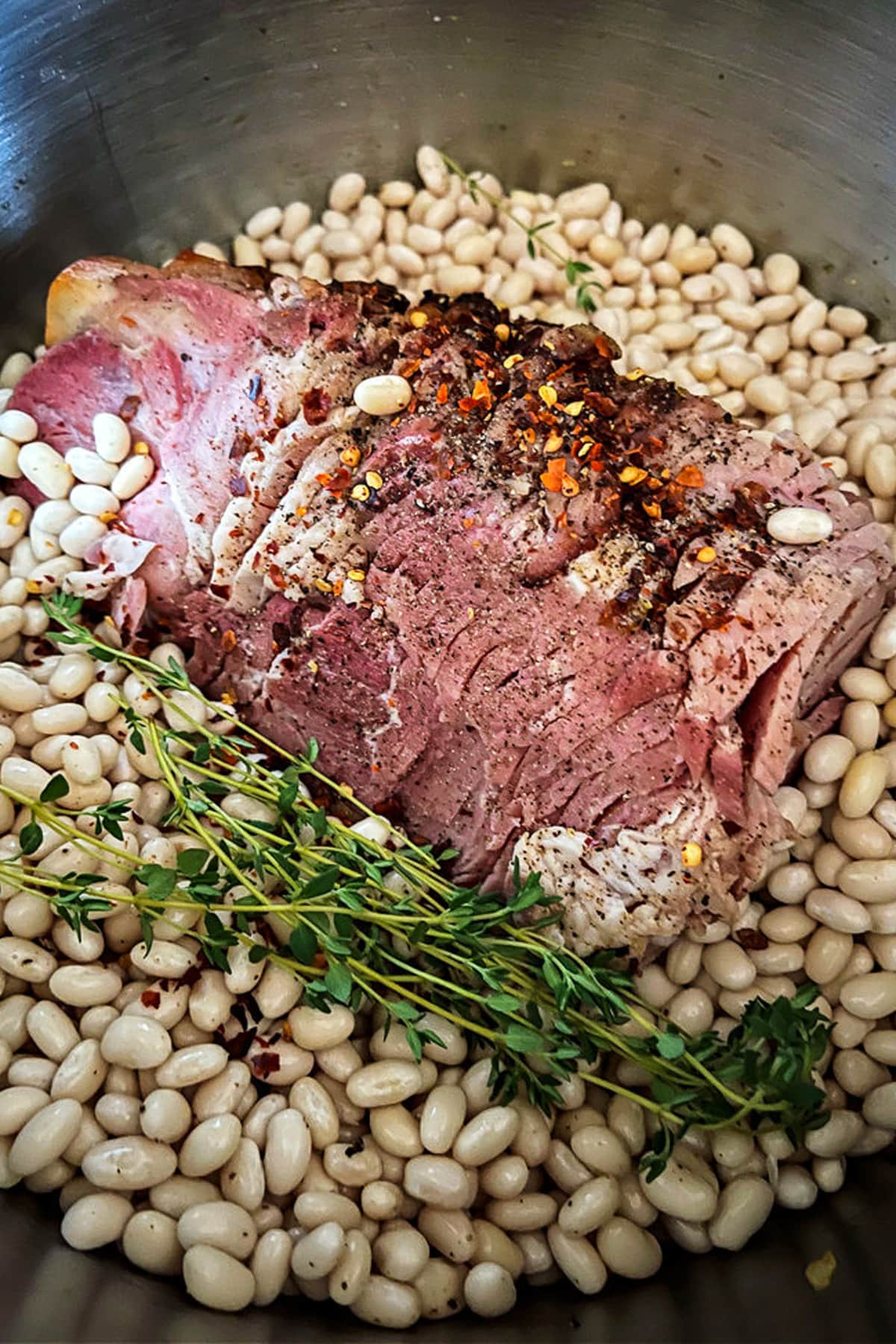 Make this comforting Navy Bean Soup with your leftover ham bone! A hearty soup loaded with vegetables in a homemade ham bone broth. ham bone in a pot with beans and herbs
