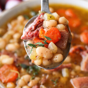 navy bean soup on a spoon over a bowl