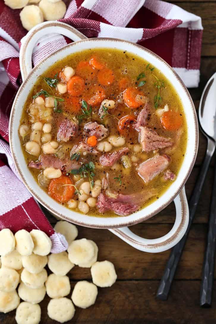 Navy Bean Soup recipe in a white bowl with crackers
