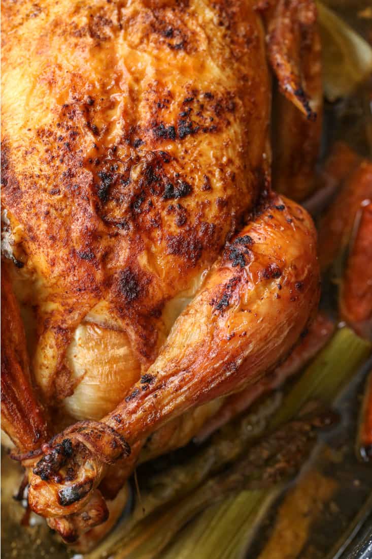 Roasted chicken in a in a baking dish with carrots and celery