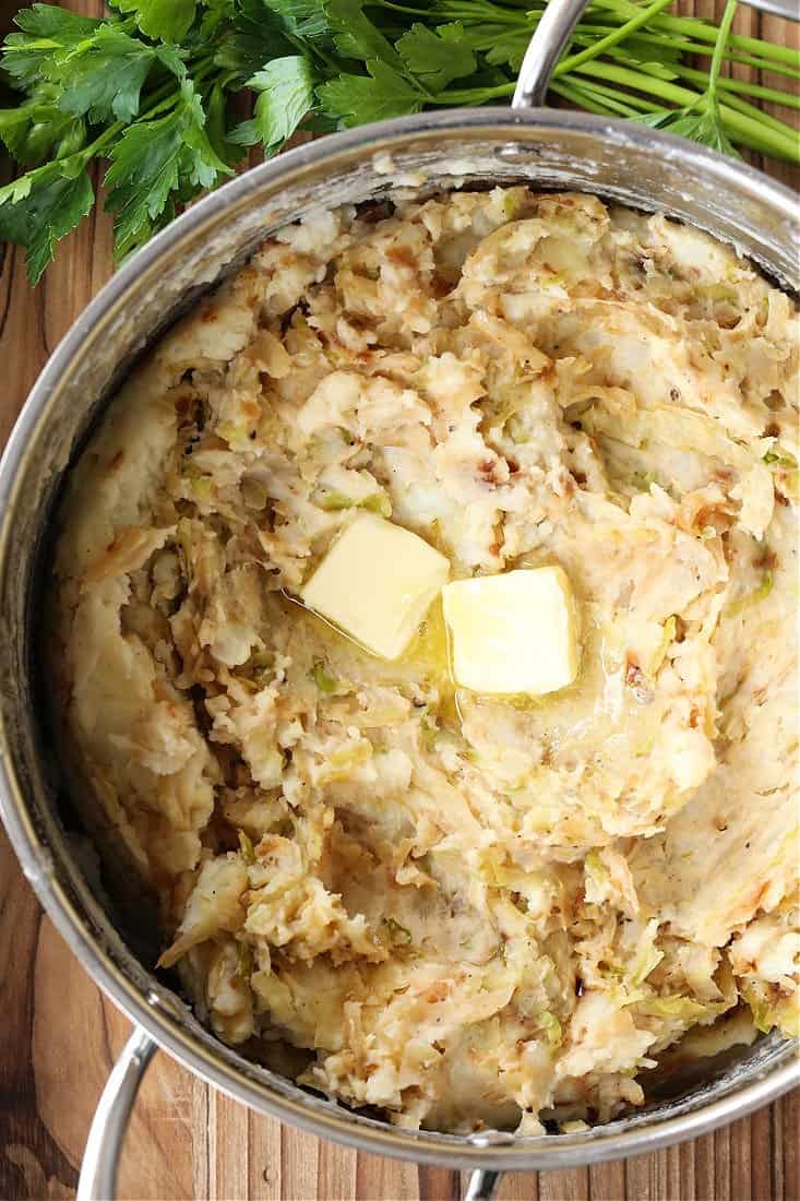 Mashed potatoes with two pats of melting butter on top in a cooking pot.