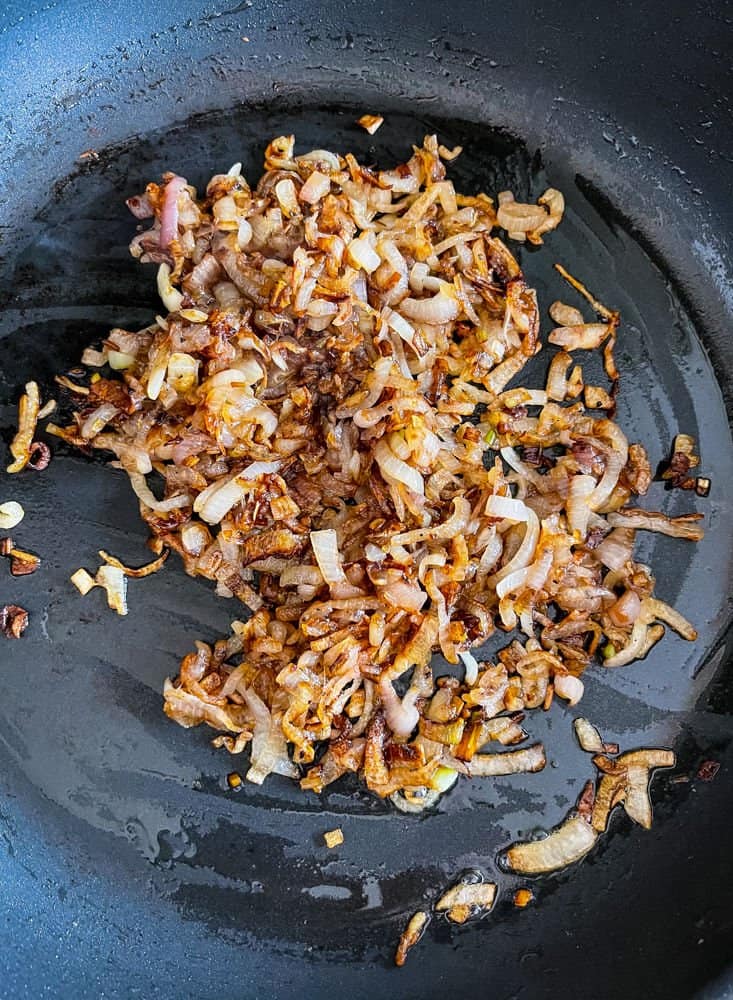 Perfectly browned caramelized onions in the bottom of a skillet with oil and butter.