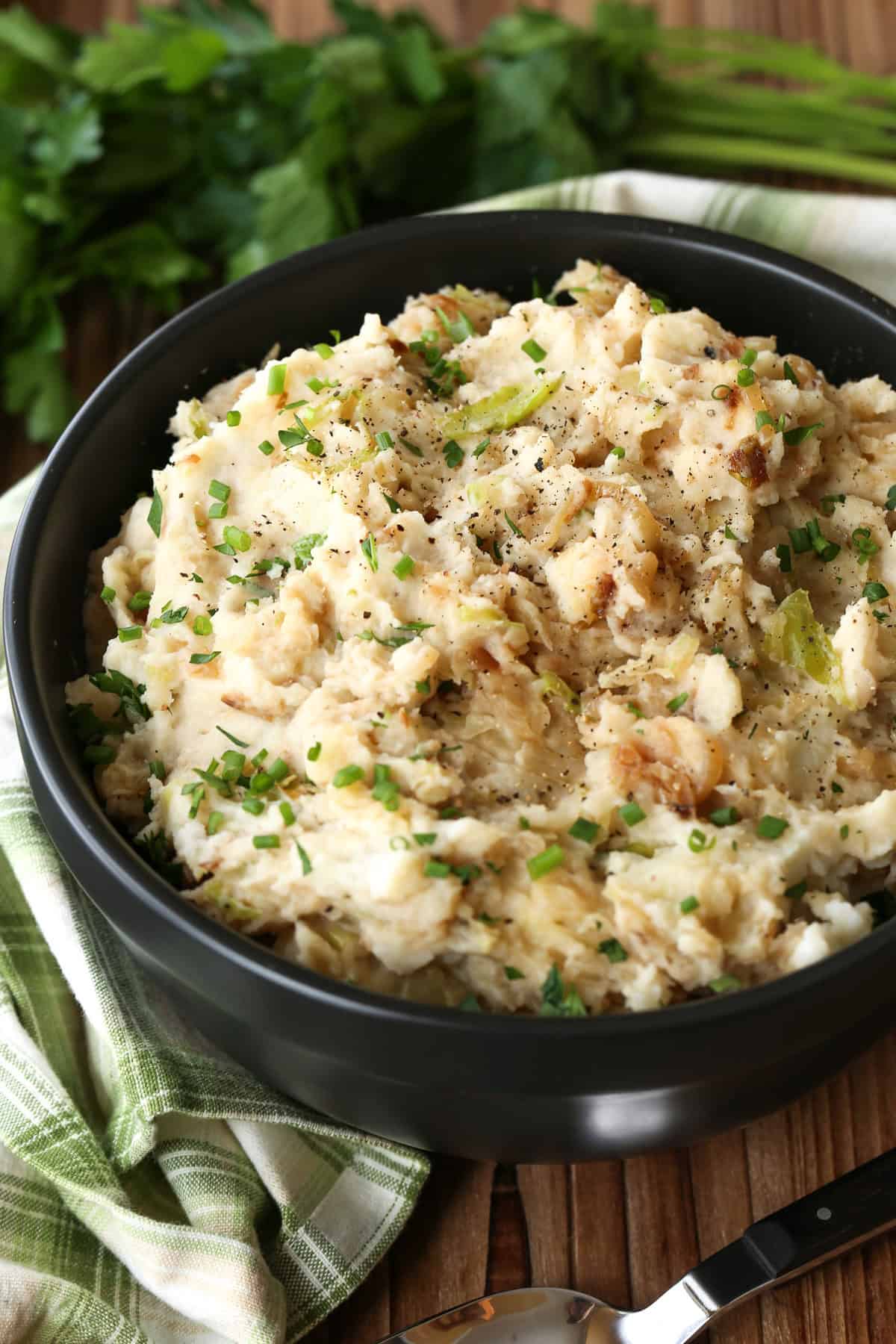 Sweet bursts of caramelized onion and the slight crunch of steamed cabbage make smooth and creamy Colcannon a Saint Patrick's Day favorite. mashed potatoes with onions and cabbage in black bowl