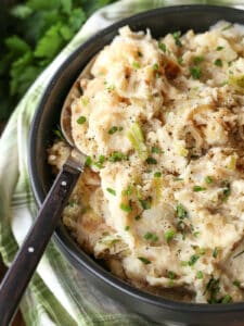 mashed potatoes with onions and cabbage in a bowl with spoon