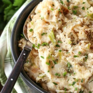 mashed potatoes with onions and cabbage in a bowl with spoon