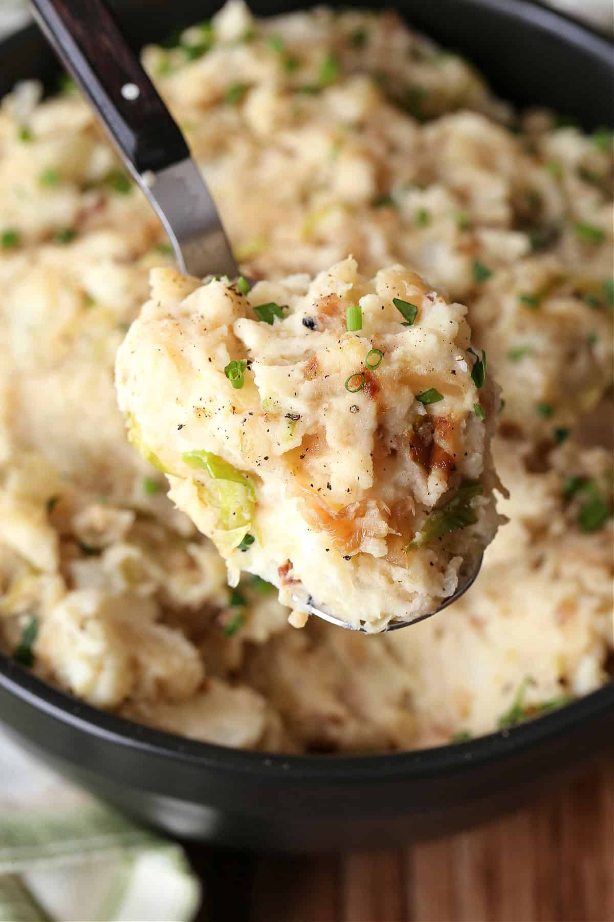This Colcannon recipe is a St. Patrick's Day favorite! Creamy, buttery mashed potatoes blended with sweet caramelized onions and cabbage. spoon with mashed potatoes and cabbage over bowl